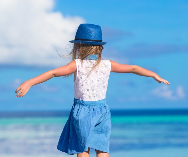 little girl in hat at beach - Asilo Bilingue